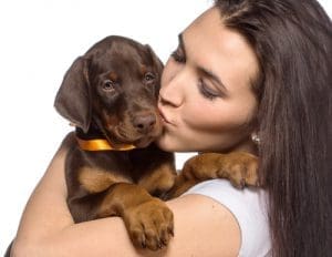 A woman holding a puppy and giving it a kiss