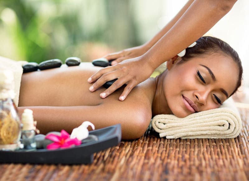 A woman getting a massage and hot stone treatment