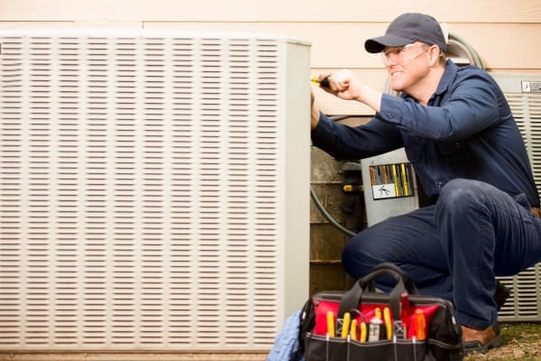 An HVAC technician working on an AC unit